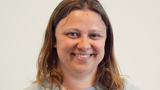 Elke heeft donkerblond haar. Ze draagt een lichtgrijs t-shirt