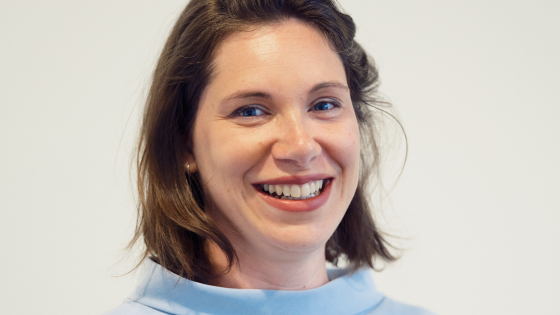Elise heeft donkerbruin haar. Ze draagt een lichtblauwe trui