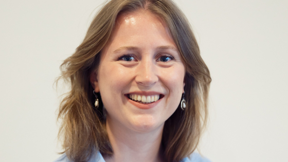 Anna heeft lichtbruin haar. Ze draagt een lichtblauwe blouse