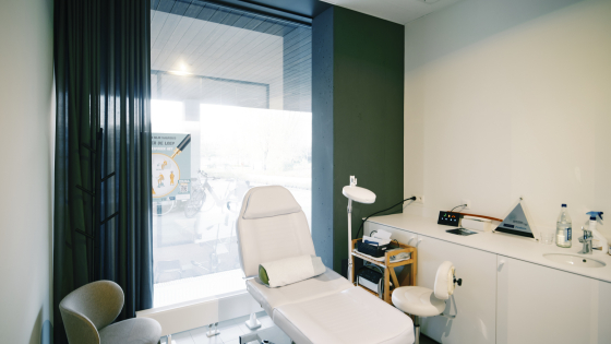 Medisch kabinet. Er staat een stoel voor een patiënt en een kleinere stoel voor de pedicurist. 