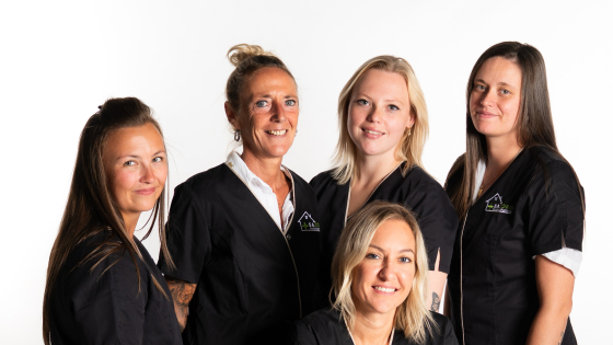 Groepsfoto van 5 verpleegkundigen. Ze dragen een zwarte schort