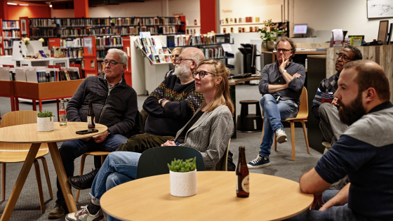 mensen die aan tafels, luisterend naar een spreker