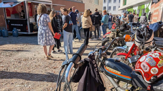 Foto van fietsen en motors op de voorgrond en mensen op achtergrond