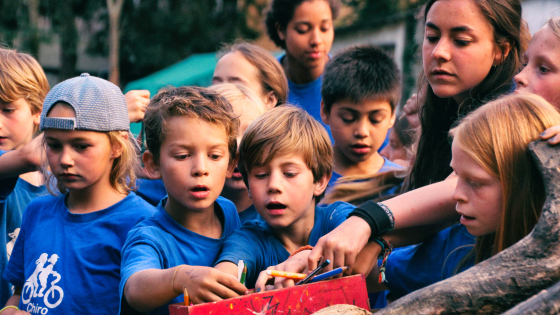 Kinderen en begeleiding staan rond elkaar en nemen een kleurpotlood