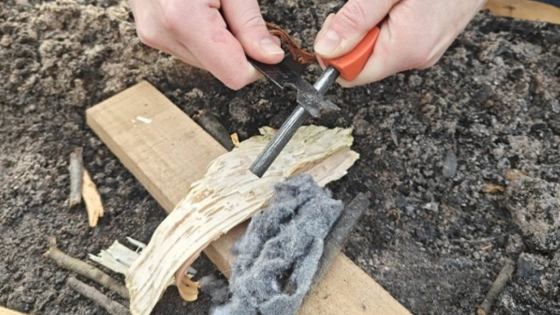 Close up van iemand die met een magnesiumstick vuur probeert te maken