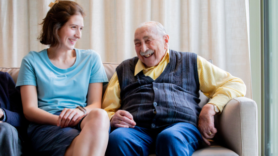 Een bewoner van het rusthuis een een verzorgster zijn in gesprek in een zetel. Ze lachen allembei