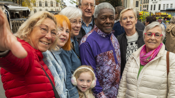 Groep van enthousiaste ouderen en een kindje op de markt van Kortrijk