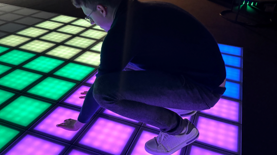 Man zit gehurkt op lichtgevende tegelvloer