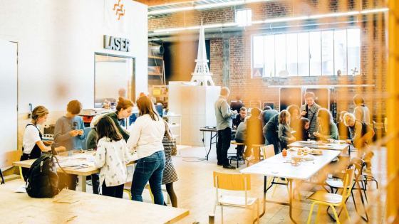 Groep mensen staat rond een tafel in de open makersspce Budalab