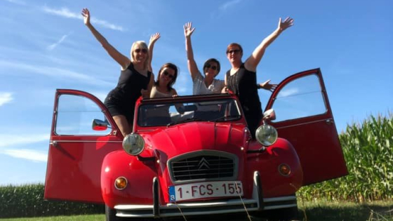 Groep vrouwen poseert in oldtimer