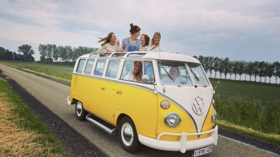 Groep mensen rijdt door de weilanden in volkswagenbusje