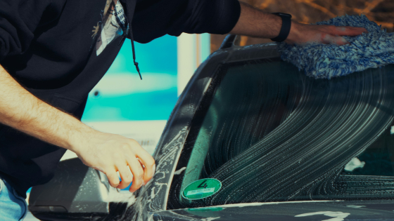 man poetst een grijze wagen