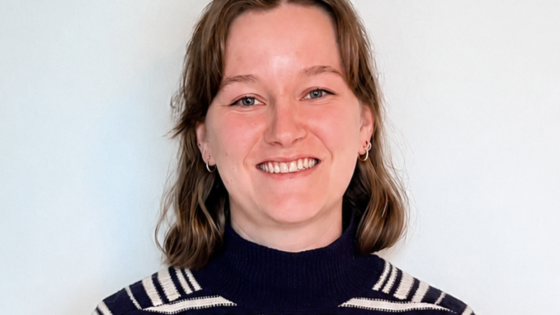 Portret van psycholoog Juliette Pollefeyt. Ze heeft schouderlang bruin haar en draagt een trui met zwarte en witte strepen