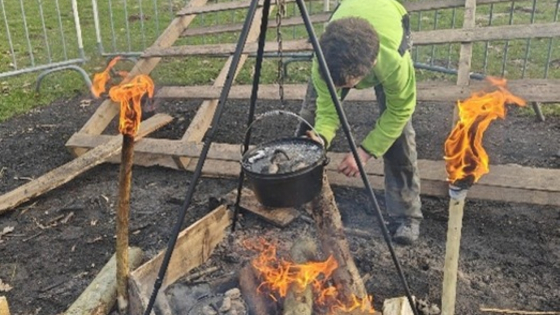 man kookt op een kampvuur
