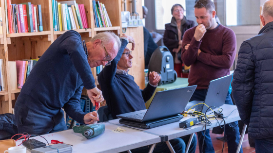 je ziet mannen die een laptop proberen repareren 