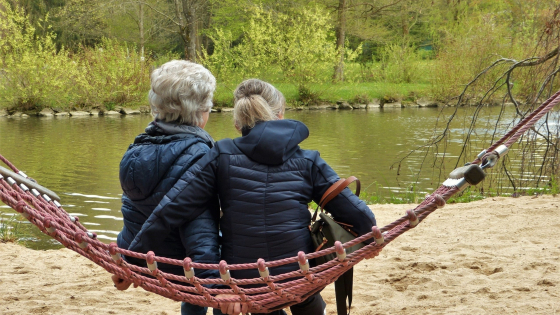 Foto van een oudere dame en jongere dame zitten op een speeltoestel