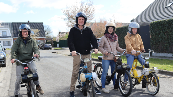 Vier mensen op een rij met een Solex