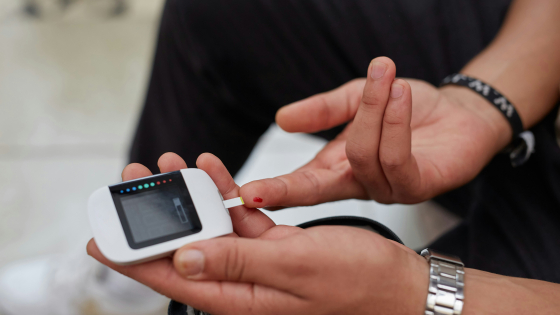 Een foto van een glucosemeter waarmee een vinger wordt aangeprikt