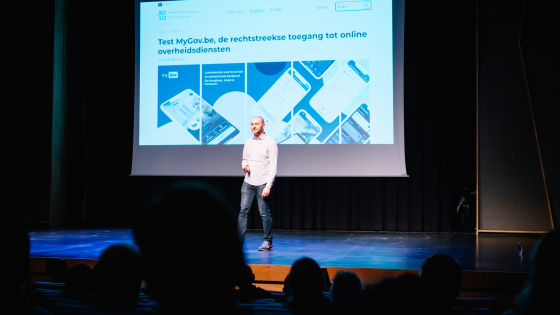 spreker digitaal jaaroverzicht 2023 op het podium van concertstudio Track Track met projectie op het scherm van het digitale jaaroverzicht 2023