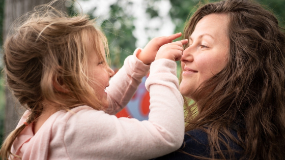 Een mama houdt haar dochtertje vast, ze lachen naar elkaar