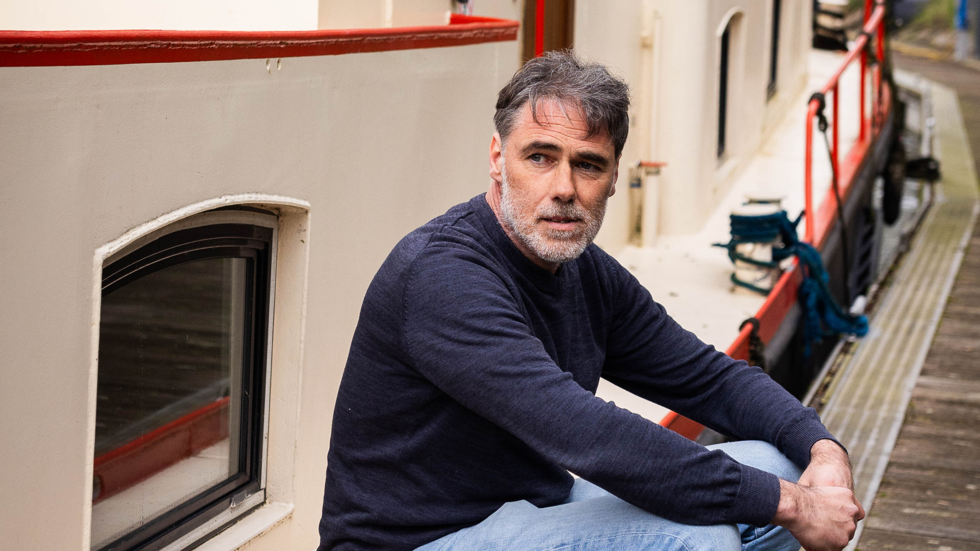 Man zit op zijkant van boot aan de steiger