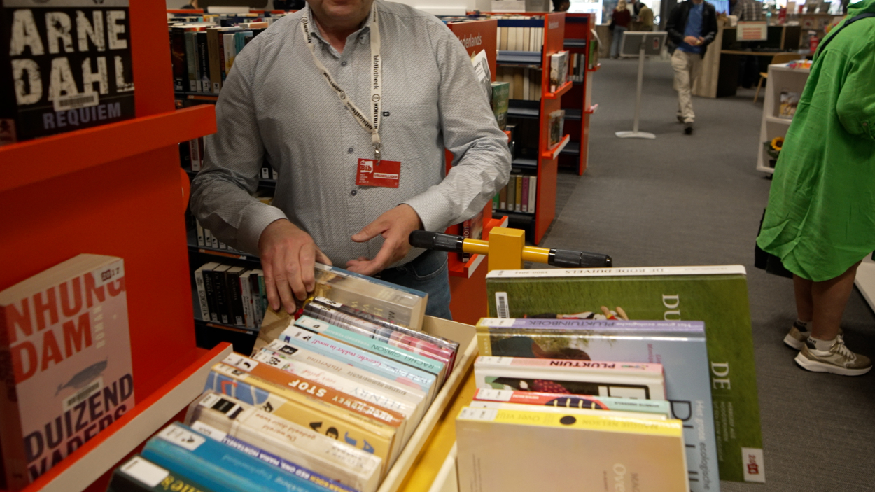 een medewerker van de bib is aan de slag met een boekenkar