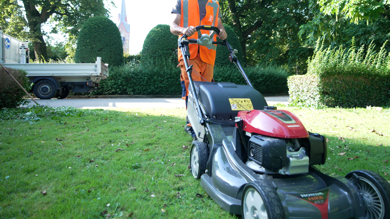 Een medewerker van de groendienst is gras aan het maaien