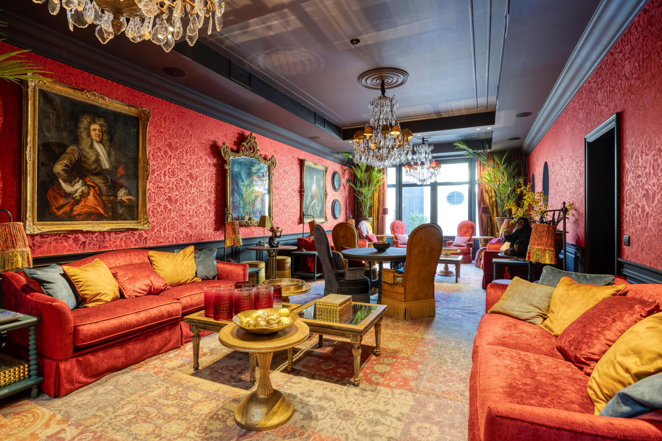 Een klassevolle en kleurrijke zaal met stoelen, tafels en zetels. Er zijn ook kroonluchters.