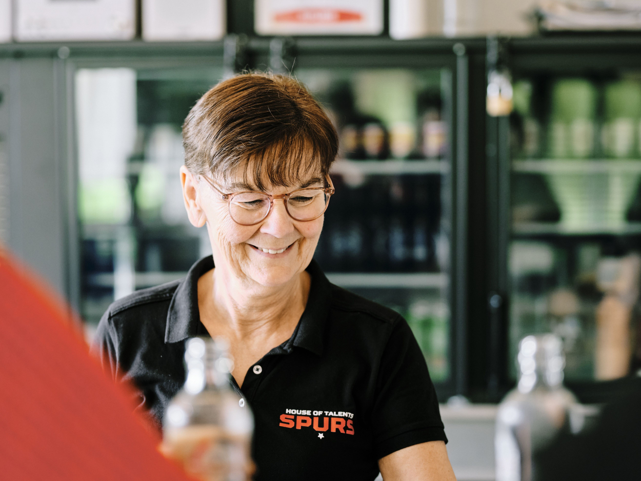 Close up van Carine die achter de bar staat