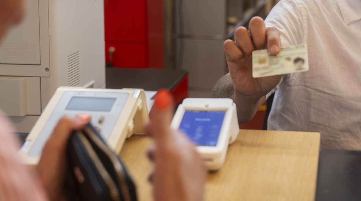 een burger geeft zijn identiteitskaart aan een medewerker van de balie