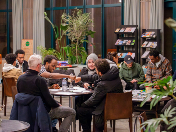 Vier mensen zitten aan een ronde tafel en praten met elkaar