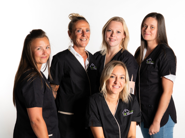 Groepsfoto van 5 verpleegkundigen. Ze dragen een zwarte schort