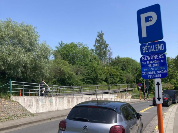 Een grijze citro&euml;n staat geparkeerd op een bewonersplaats. Die parkeerplaats is gemarkeerd met gele lijnen. Er staat een blauw parkeerbord bij met onderborden waarop informatie staat over het bewonersparkeren