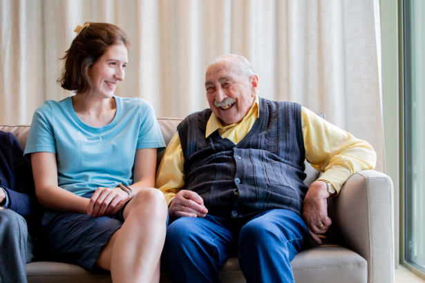 Een bewoner van het rusthuis een een verzorgster zijn in gesprek in een zetel. Ze lachen allembei