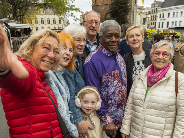 Groep van enthousiaste ouderen en een kindje op de markt van Kortrijk