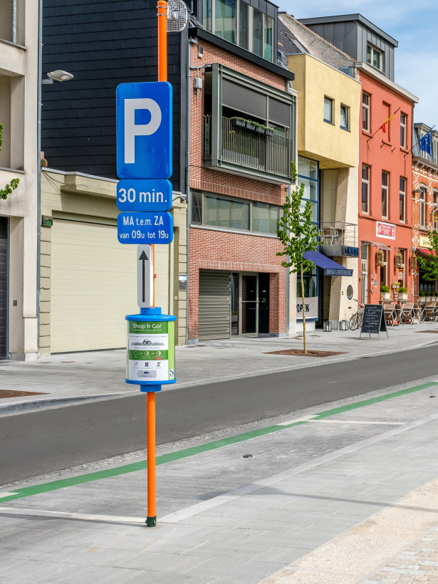 De Shop&Go-plaats is gemarkeerd met groene lijnen.  Een paal met info geeft duidelijk aan dat dit zo'n parkeerplaats is en wat de regels zijn op zo'n Shop&Go-plaats