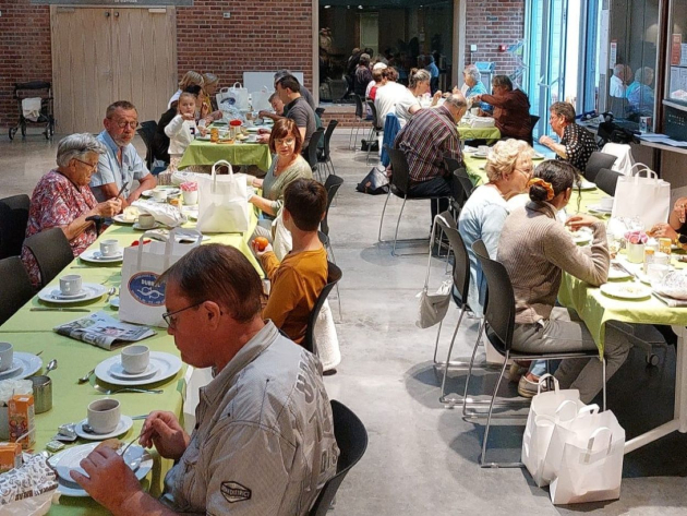 Een dertigtal mensen ontbijt aan lange tafels in het ontmoetingscentrum van Aalbeke. 