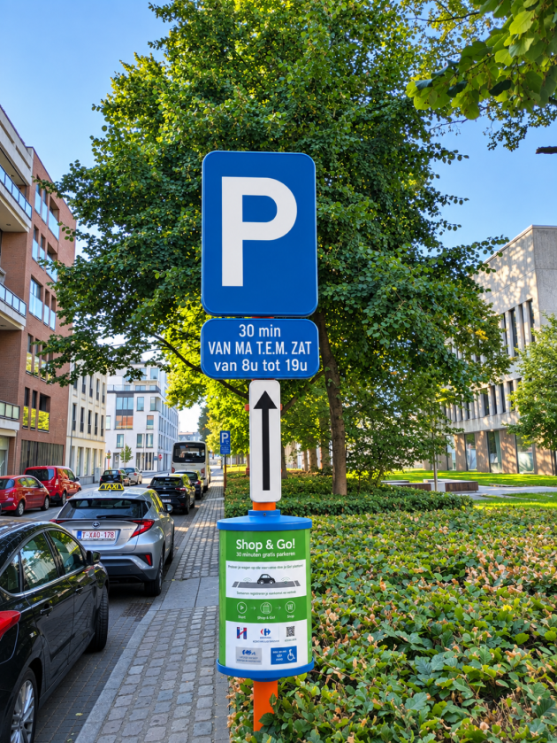 De Shop&Go-plaats is gemarkeerd met groene lijnen.  Een paal met info geeft duidelijk aan dat dit zo'n parkeerplaats is en wat de regels zijn op zo'n Shop&Go-plaats