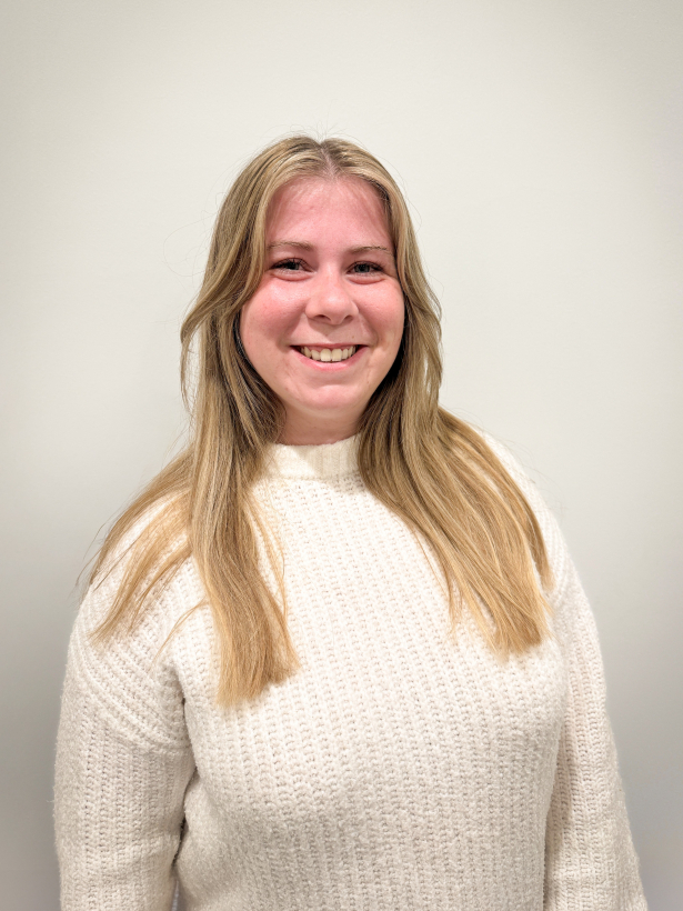 Portret van psychologisch consulent Frauke Debbaut. Femke heeft lang blond haar, draagt een witte trui en lacht vriendelijk