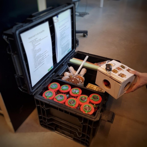 zwarte koffer met daarin een houten doos en insectenpotjes