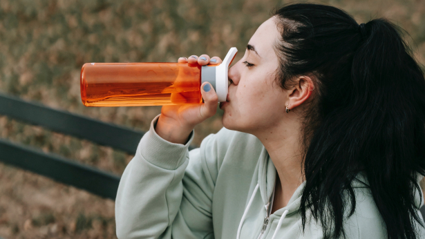 meisje drinkt uit een oranje drinkfles