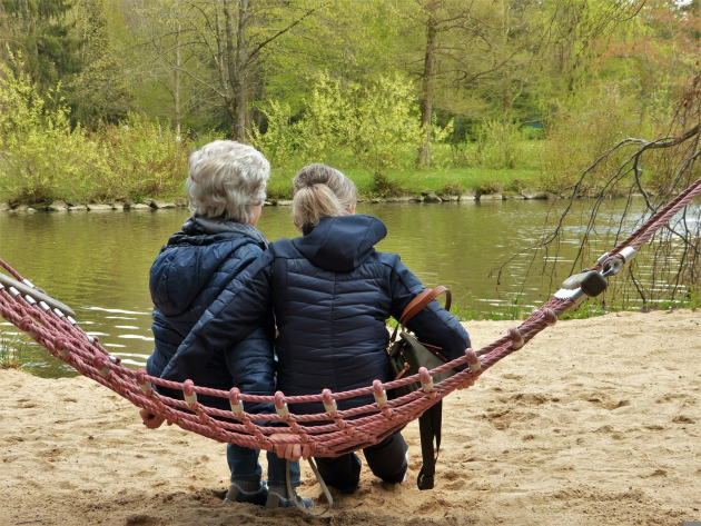 Foto van een oudere dame en jongere dame zitten op een speeltoestel