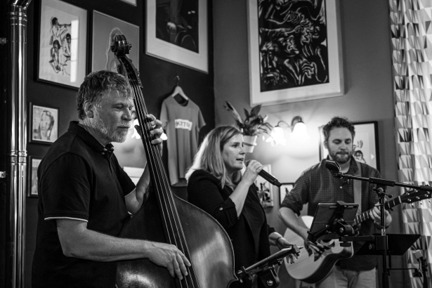 Het trio threesome geeft een optreden. een man aan een contrabas, een dame zingt, een man speelt gitaar
